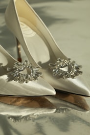 A pair of elegant, high-end shoes with sparkling embellishments displayed on a marble surface.