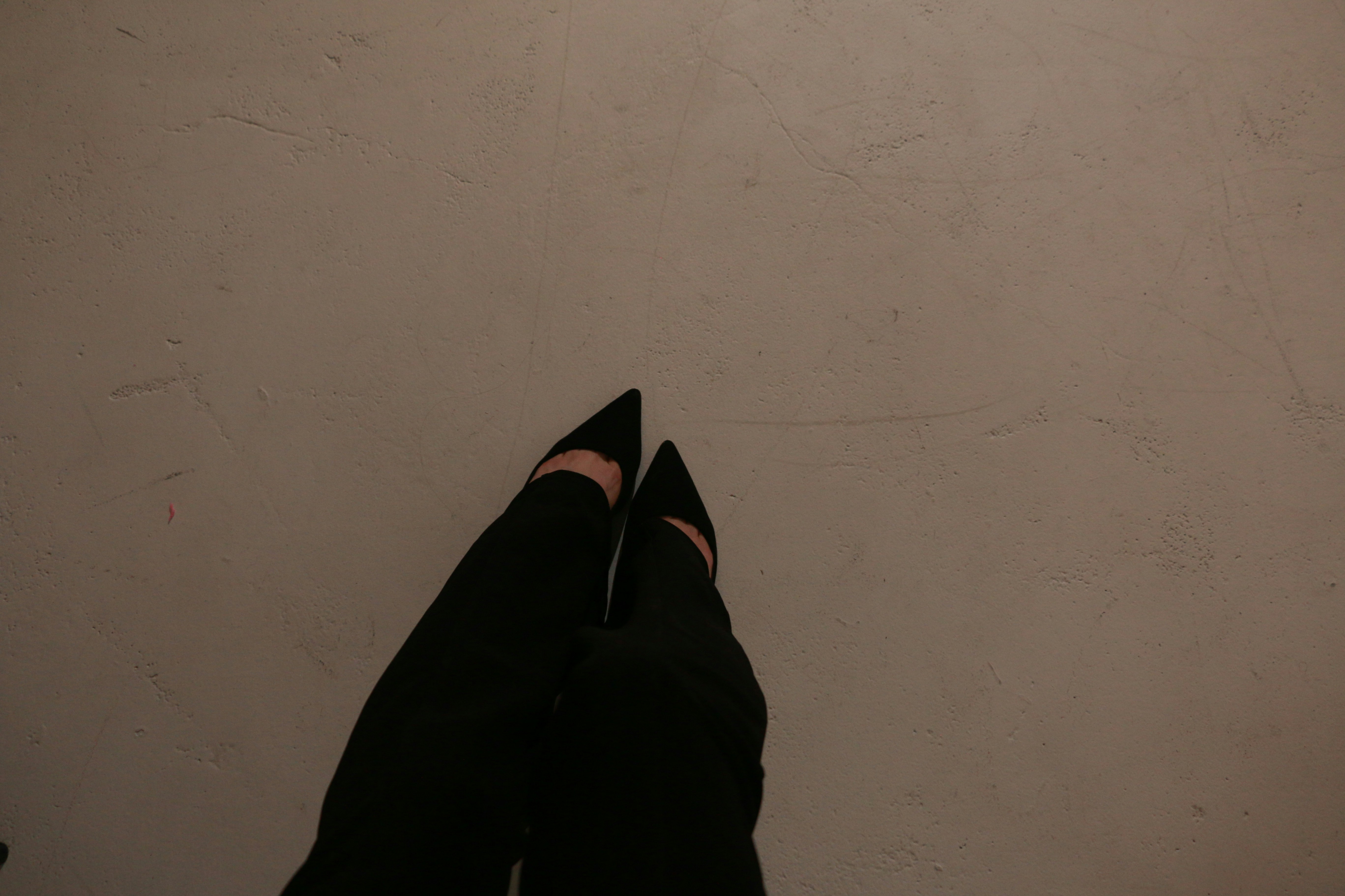 a person wearing black shoes standing in front of a white wall