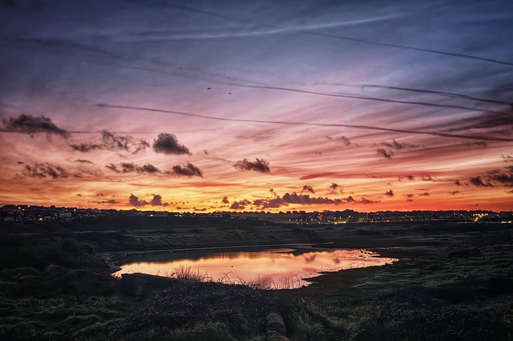 a sunset over a body of water with clouds in the sky