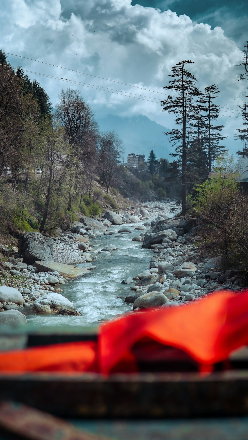 a red umbrella sitting on the side of a river