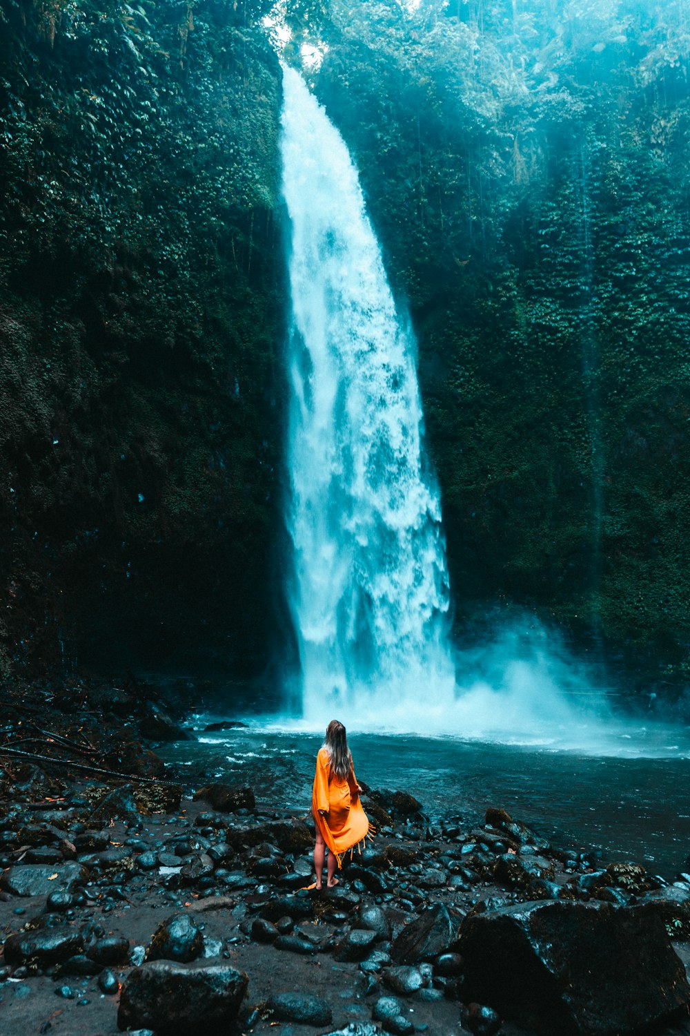 a woman standing in front of a waterfall