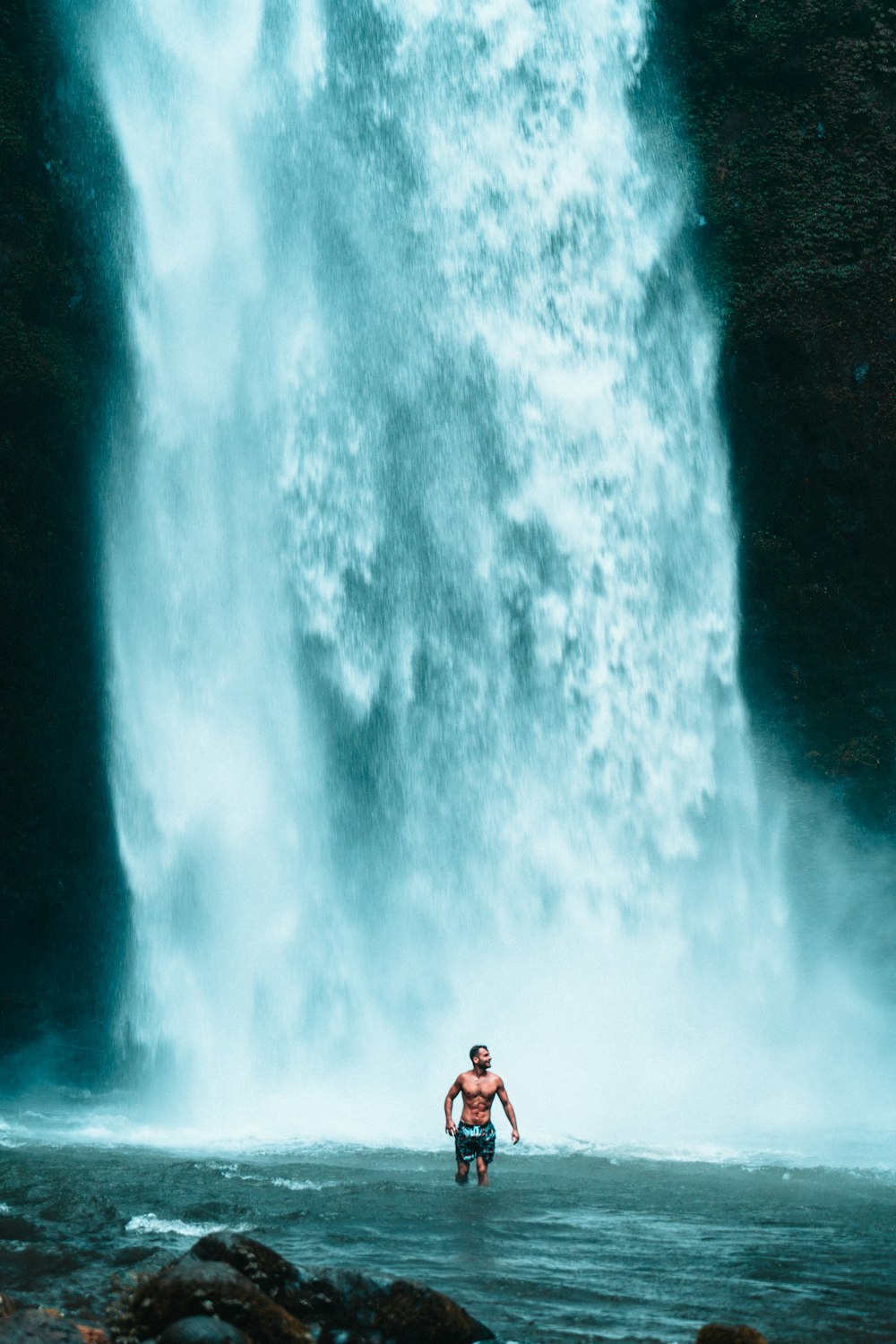 a man riding a surfboard in front of a large waterfall