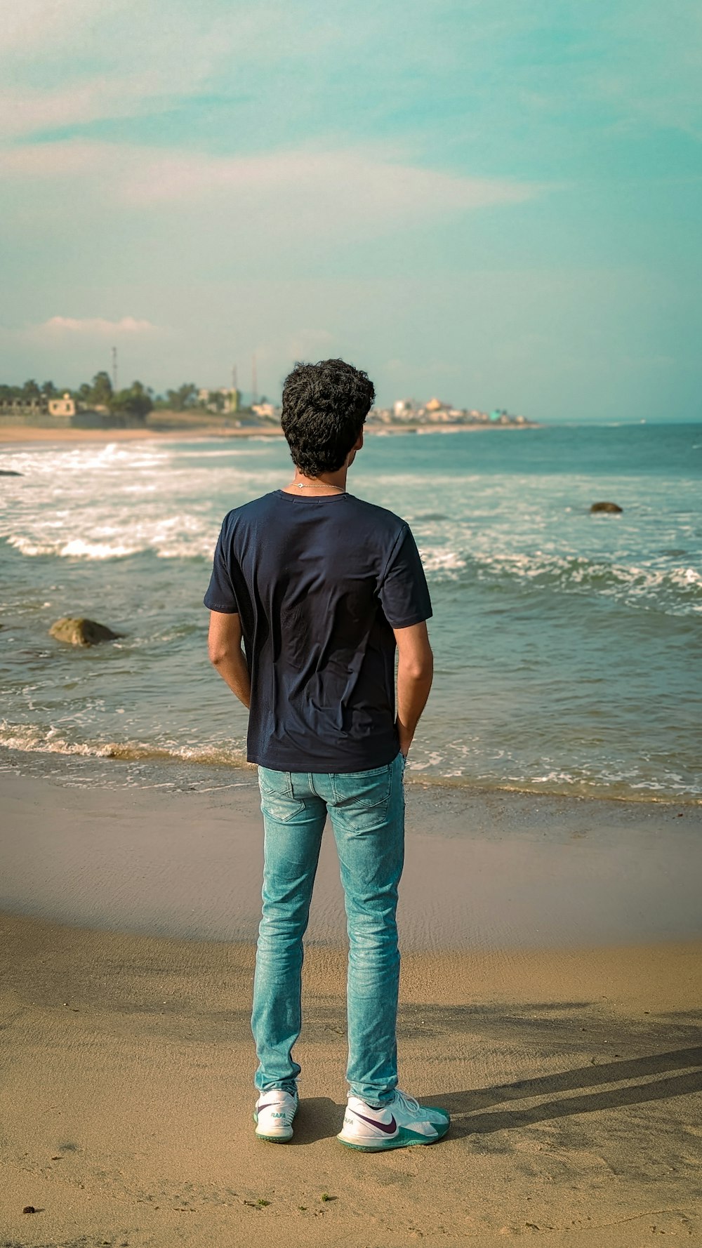 un uomo in piedi sulla spiaggia che guarda l'oceano