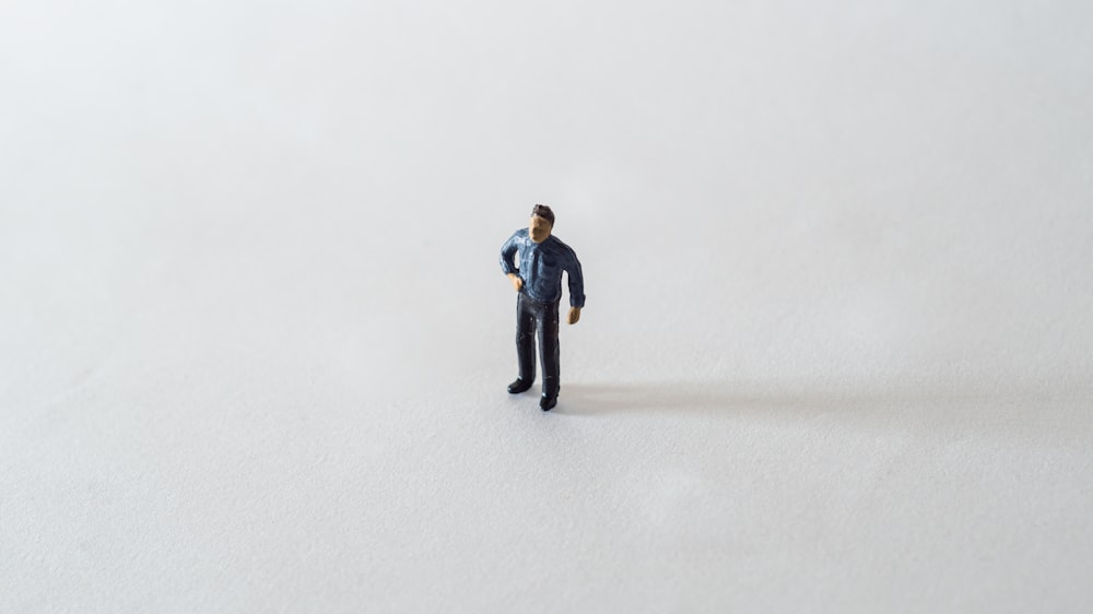 a miniature man standing in the middle of a snow covered field