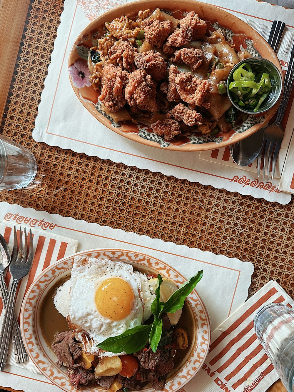 two plates of food on a table with utensils