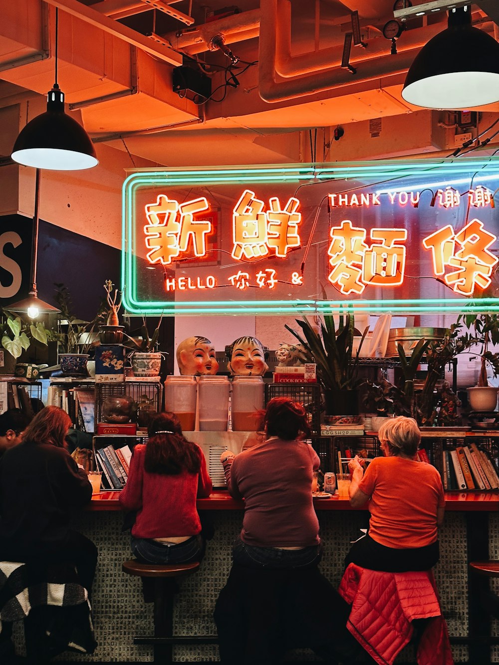 a group of people sitting at a table in front of a neon sign