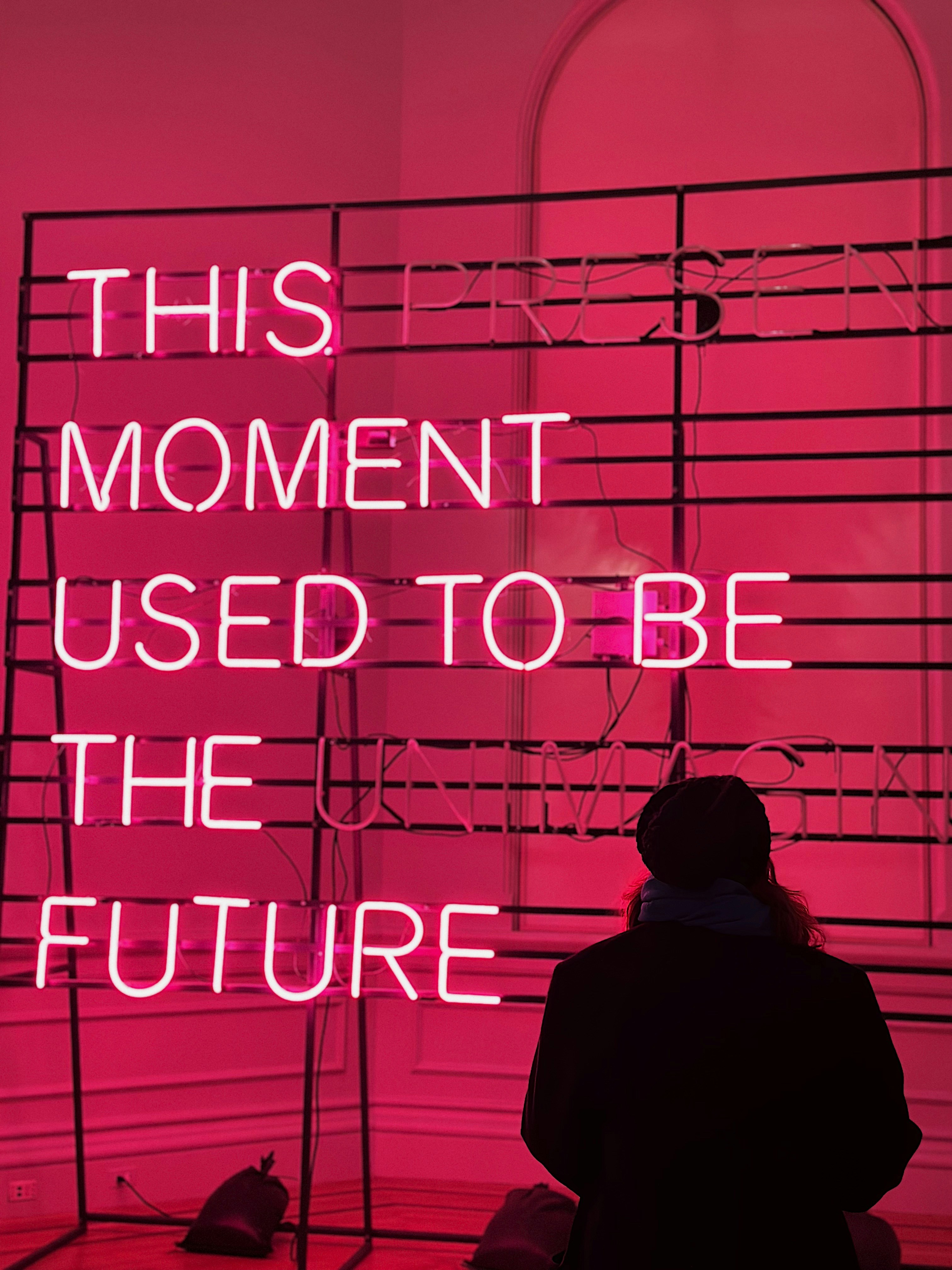 a person standing in front of a pink neon sign