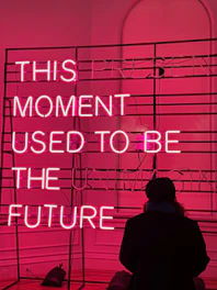 a person standing in front of a pink neon sign