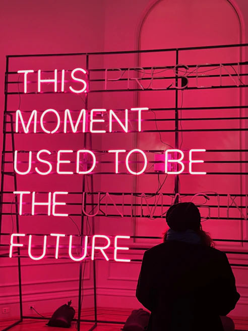 a person standing in front of a pink neon sign