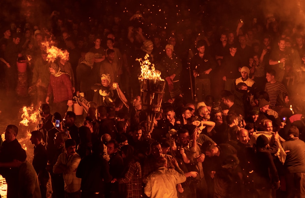 a crowd of people standing around a fire pit