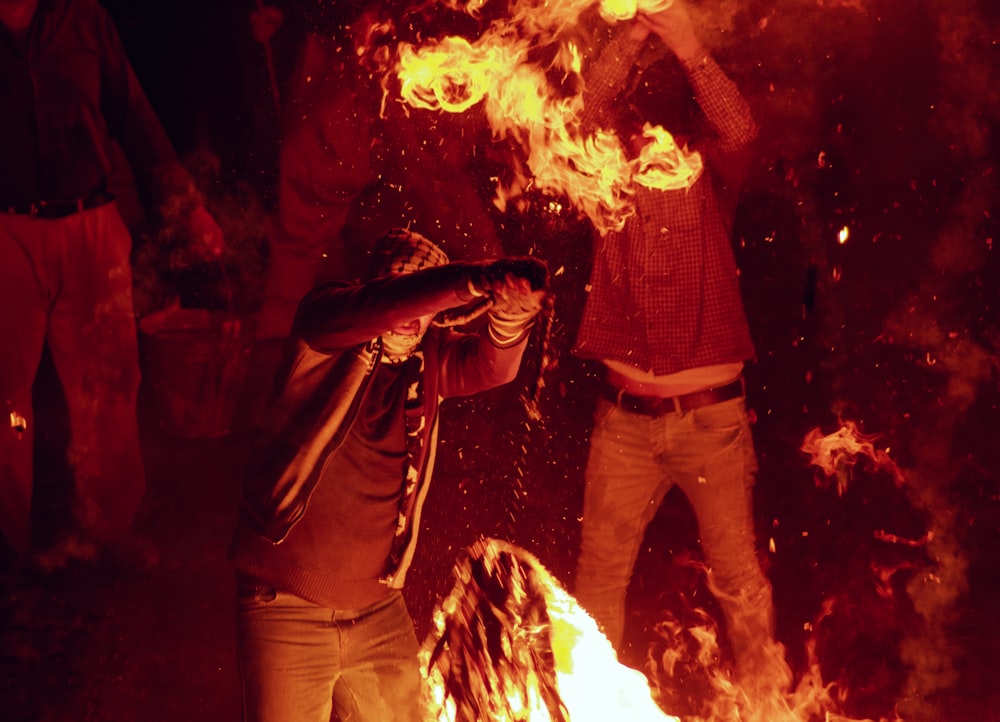 two men standing in front of a fire