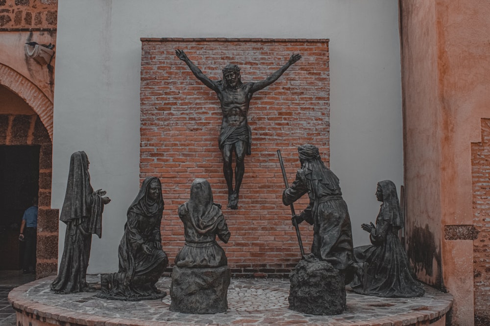 eine Statue eines Kruzifixes vor einer Backsteinmauer