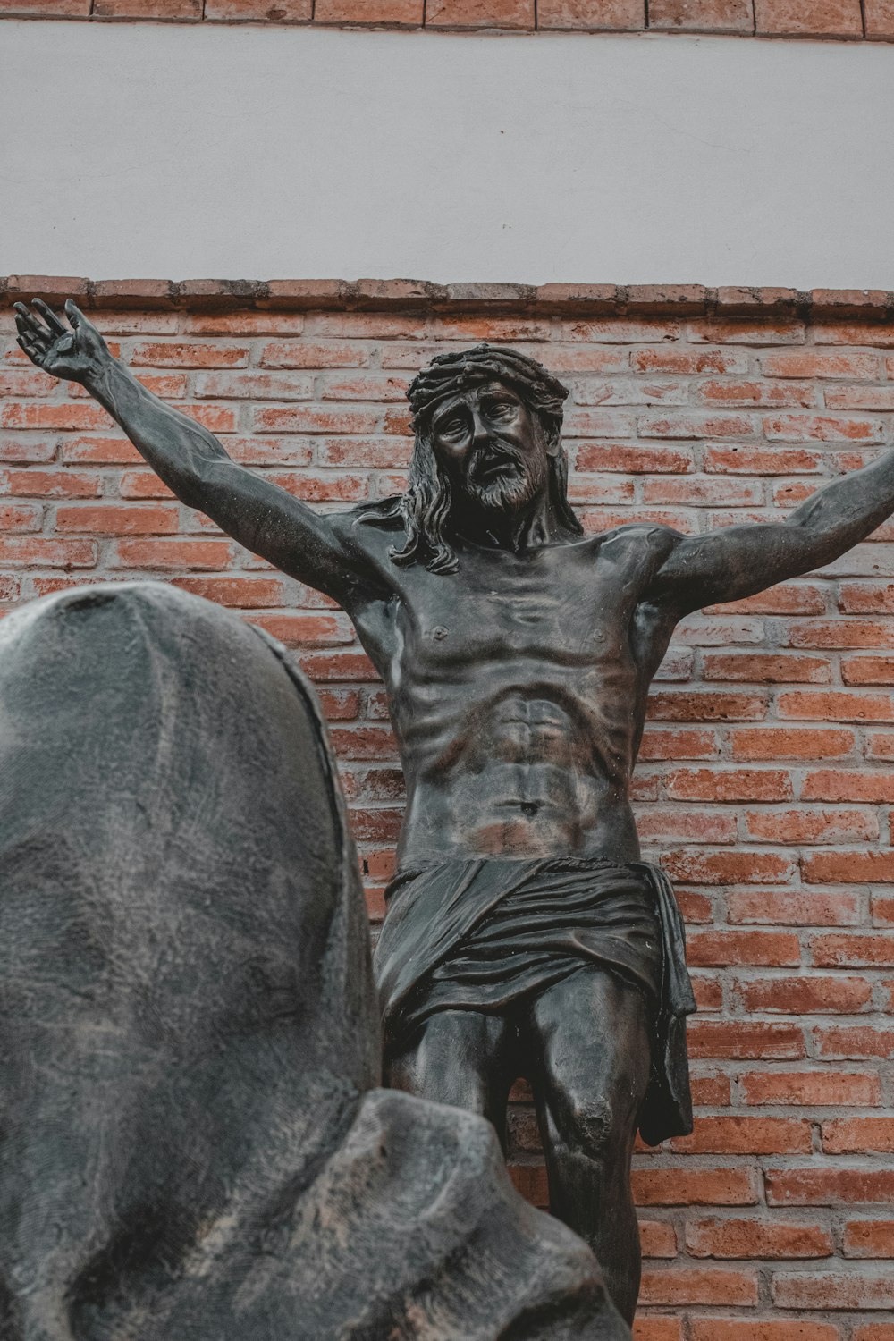 a statue of a man with his hands up in front of a brick wall