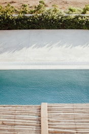 A bright, inviting swimming pool surrounded by lush greenery and Acqua branded pool products neatly arranged nearby.