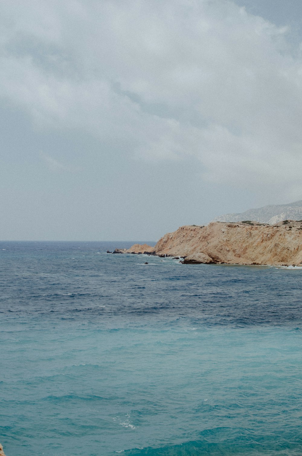 a large body of water sitting next to a rocky shore