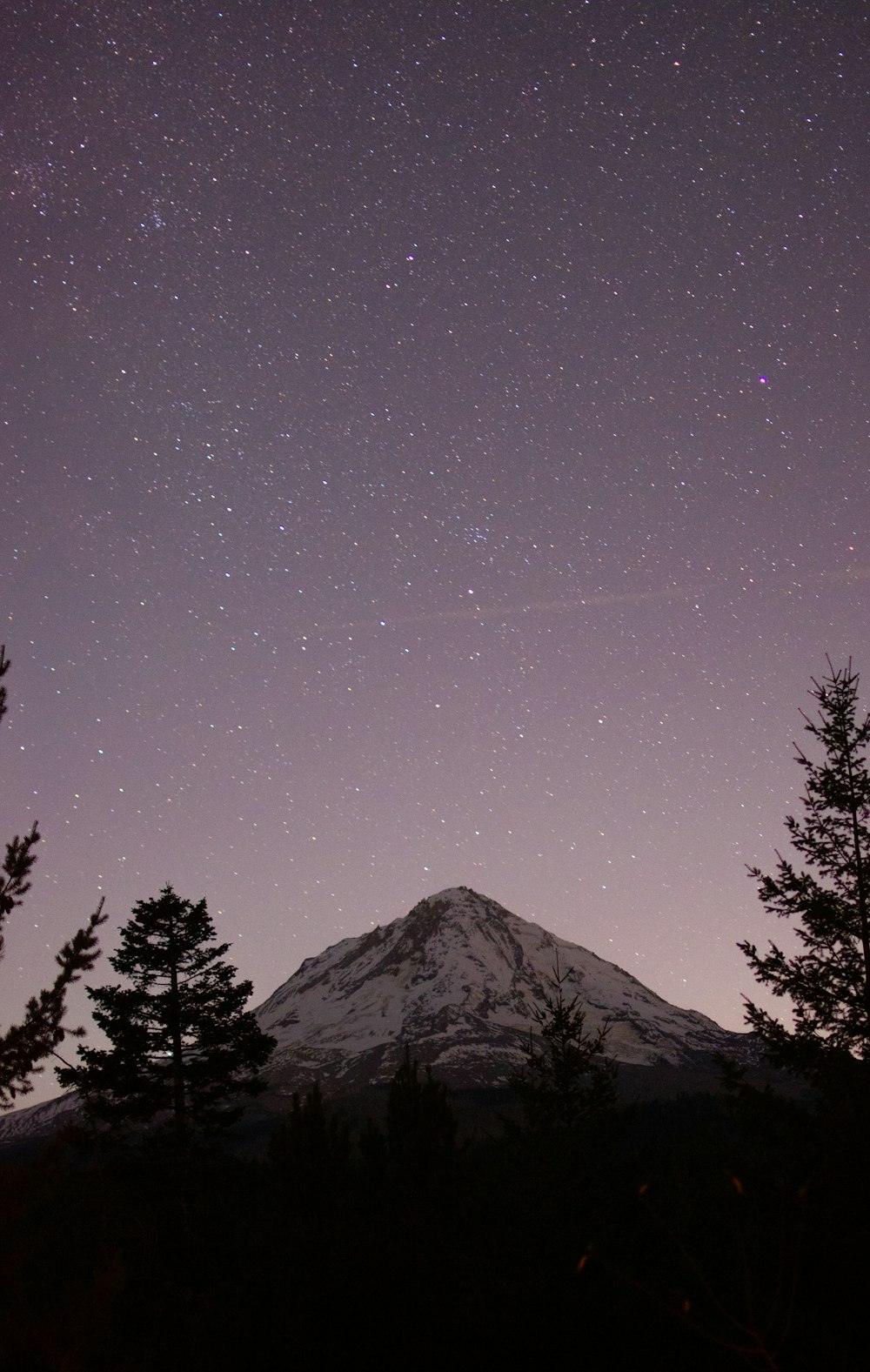 a snow covered mountain under a purple sky