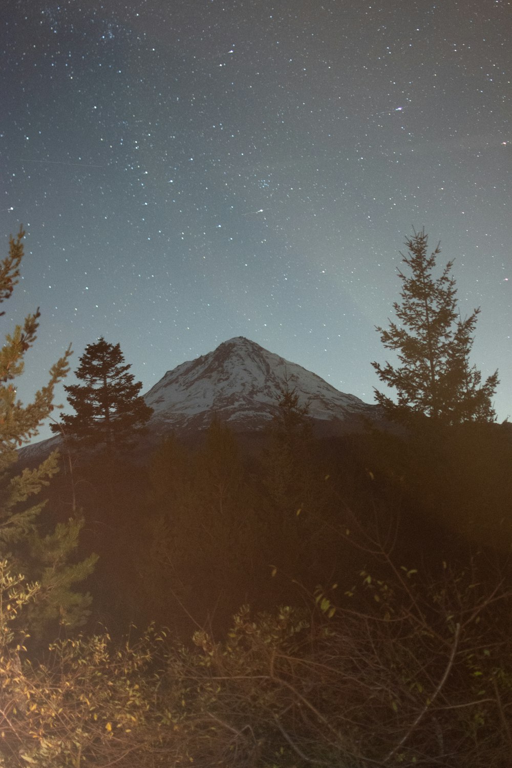 a night sky with stars above a mountain