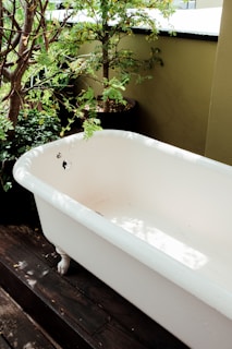 Before and after shots of a bathtub transformed by a new acrylic inset, photographed in natural light.