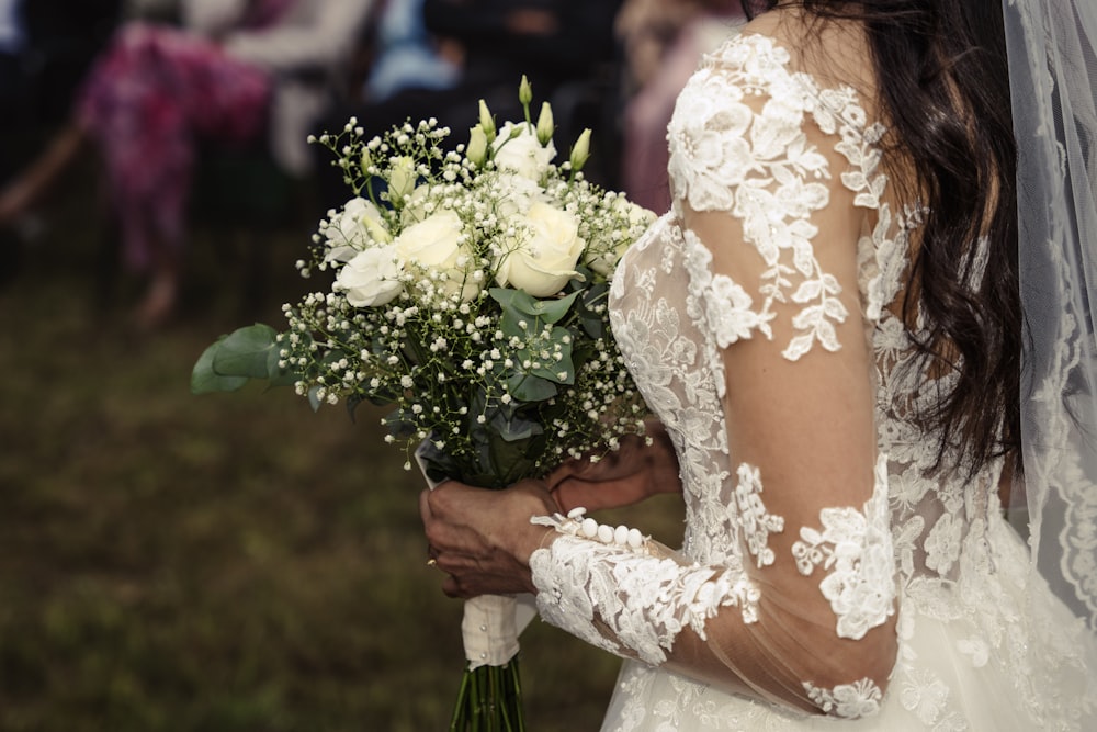 a bride holding a bouquet of white roses