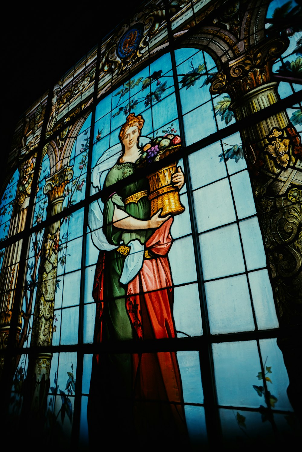 a stained glass window with a woman holding a basket of flowers