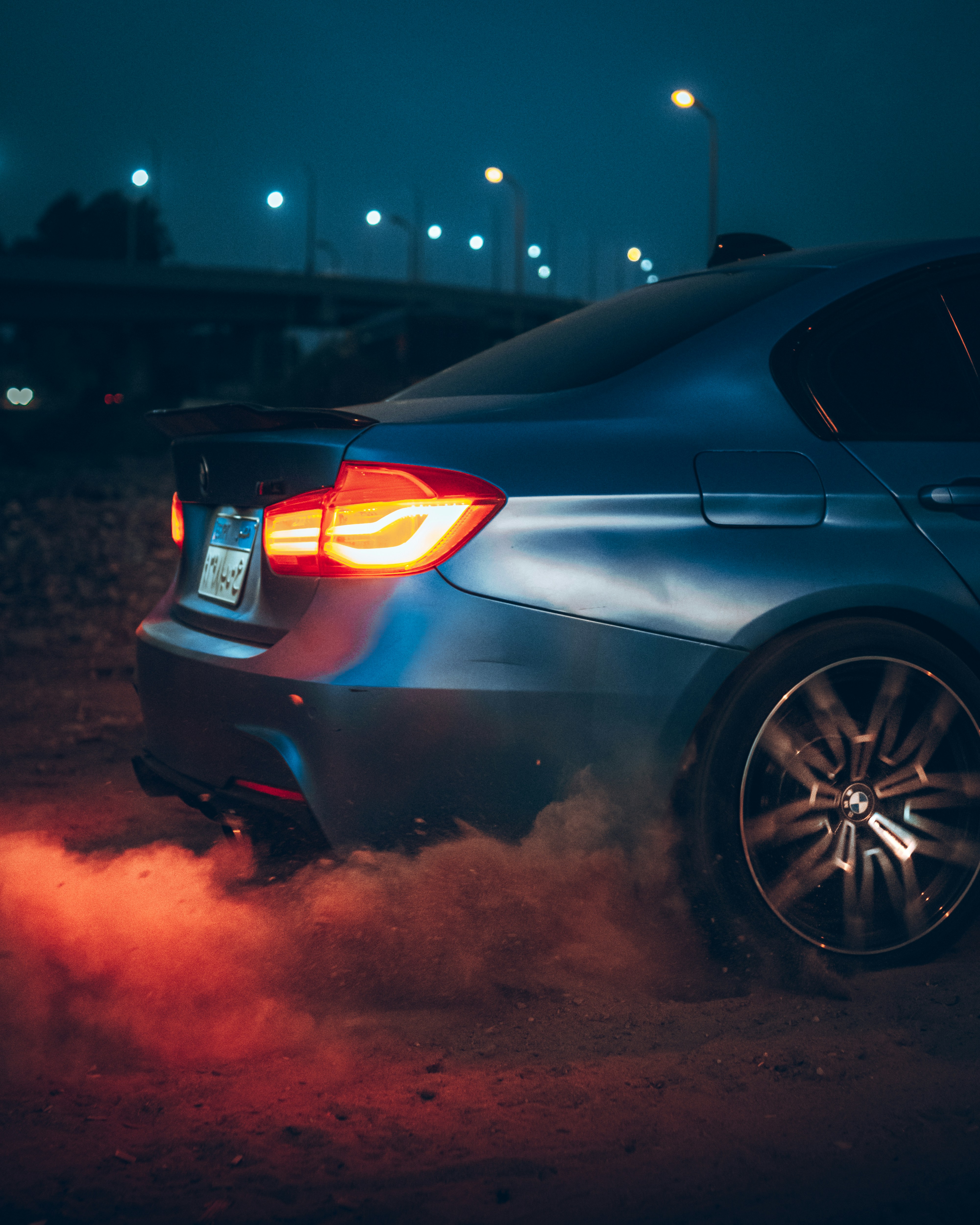 a blue car driving down a street at night