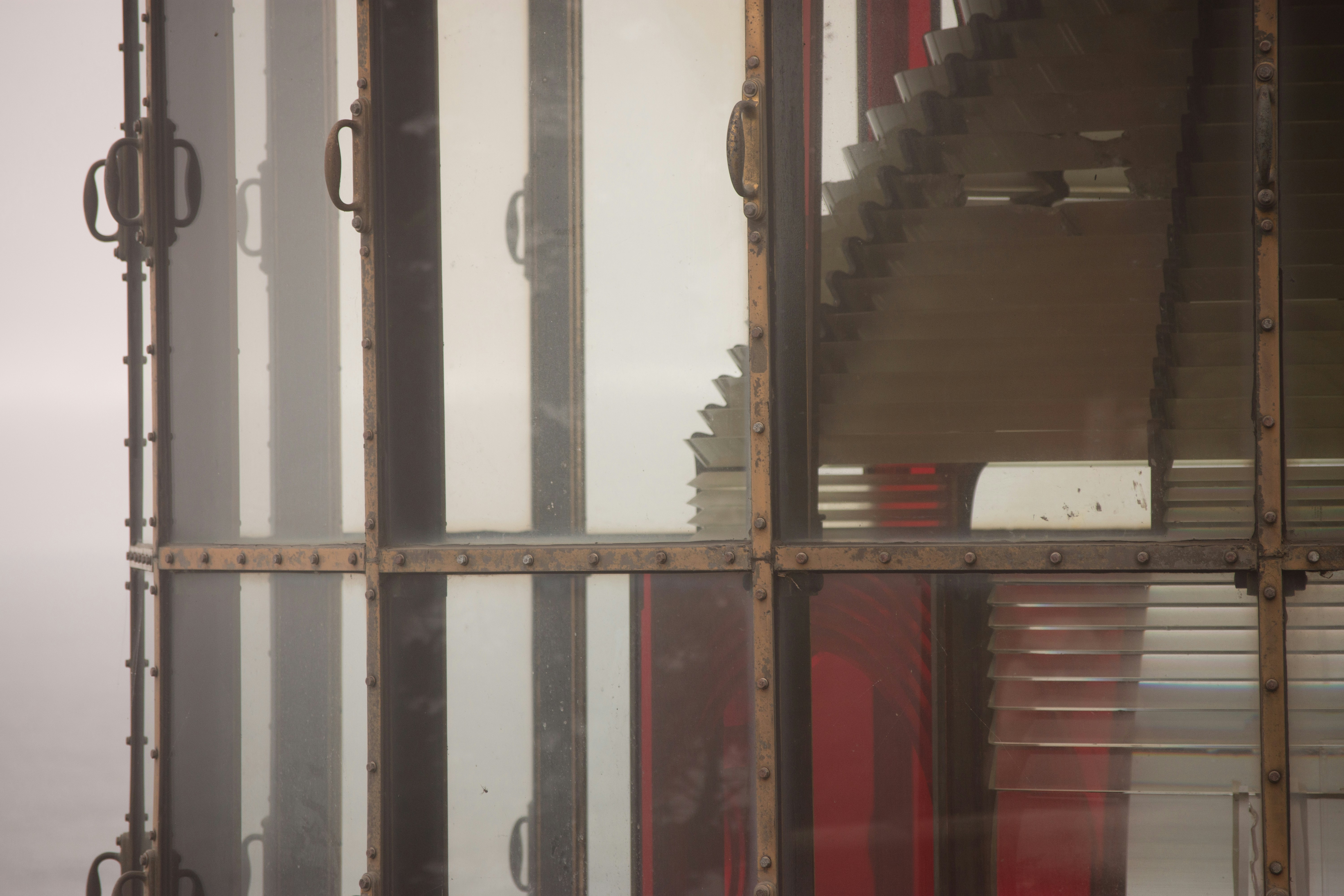 a window that has a bunch of windows in it, Once a necessary beacon of safety, the Cape Meares Lighthouse now lies unused and partially abandoned. We look on it now as a relic of the past, but how many lives did this one building save? Lodestar.