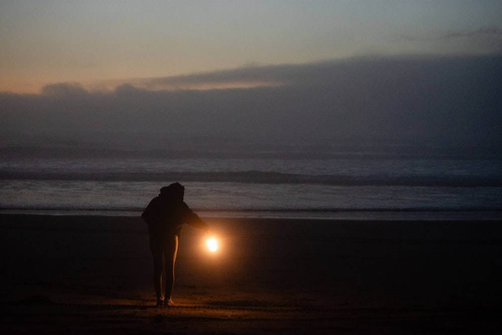 a person standing on a beach with a flashlight in their hand