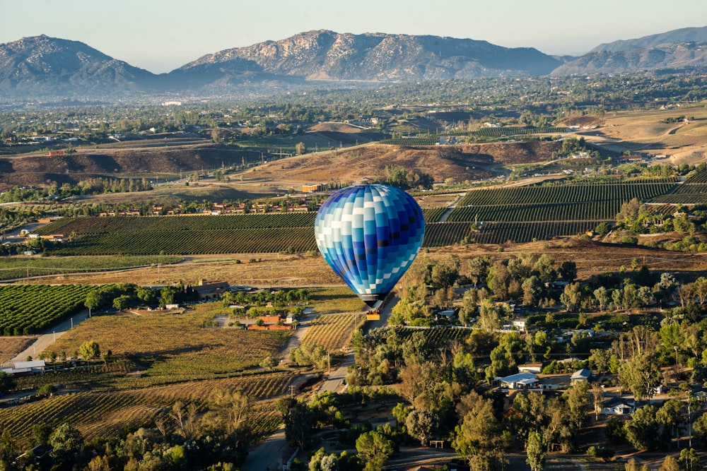 a hot air balloon flying over a lush green hillside