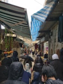 A crowded market in Thailand with people seeking shelter from the rain.