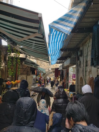 A crowded market in Thailand with people seeking shelter from the rain.