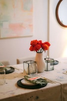 A modern dining table set with neutral-toned placemats, simple ceramic plates, and a delicate centerpiece.