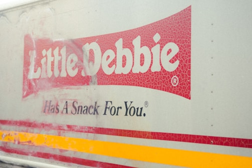 A truck with the Little Debbie logo and the slogan 'Has A Snack For You.' The logo is prominently displayed with a cracked texture on a red background.