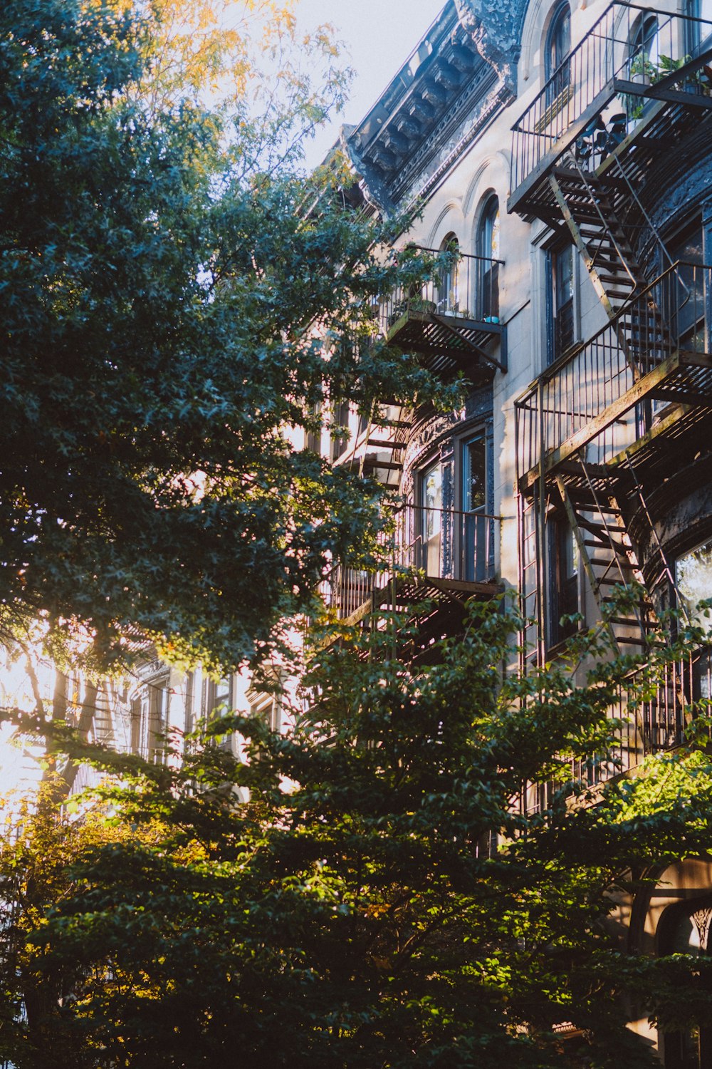 a tall building with a fire escape next to trees