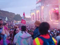 An outdoor festival scene with colorful banners and a crowd enjoying a live performance.