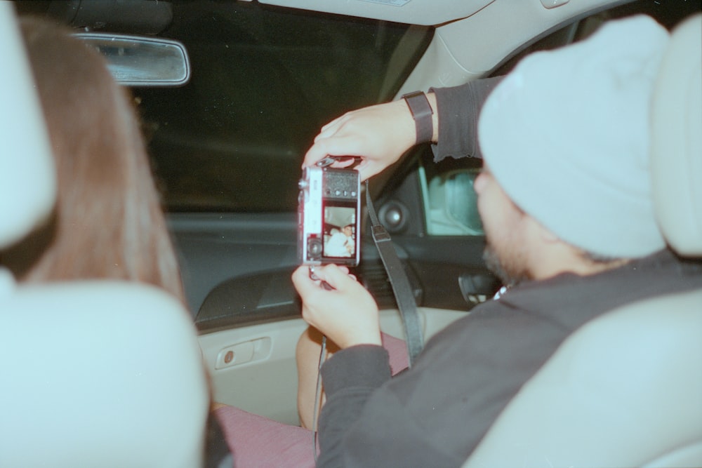 a man taking a picture of a woman in a car