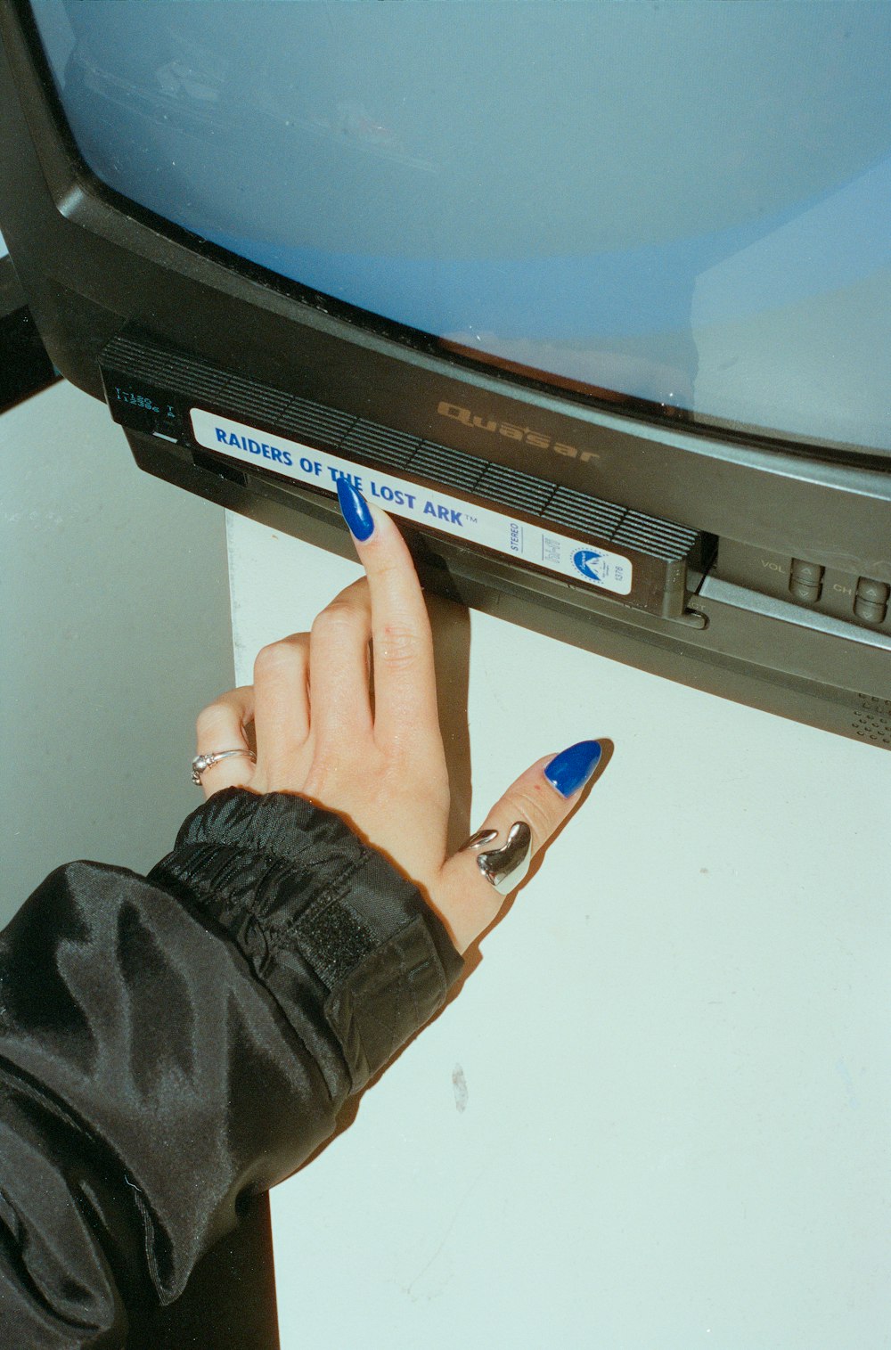 a person with a blue manicure is touching a television