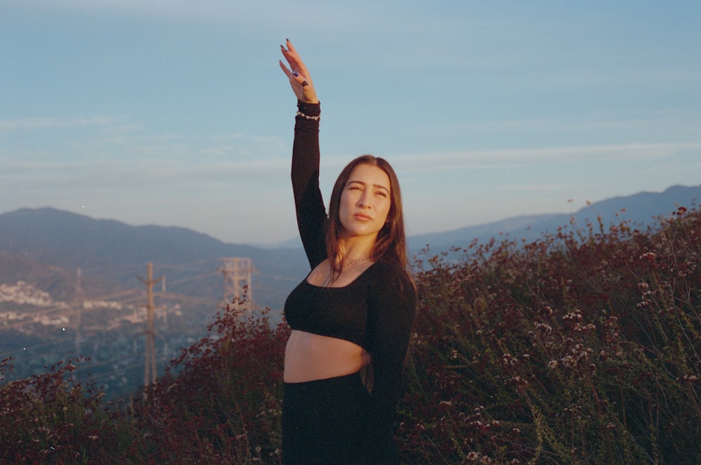 a woman standing on top of a lush green hillside