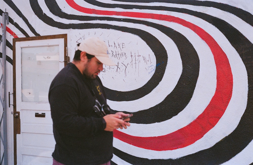 a man standing in front of a wall with a cell phone