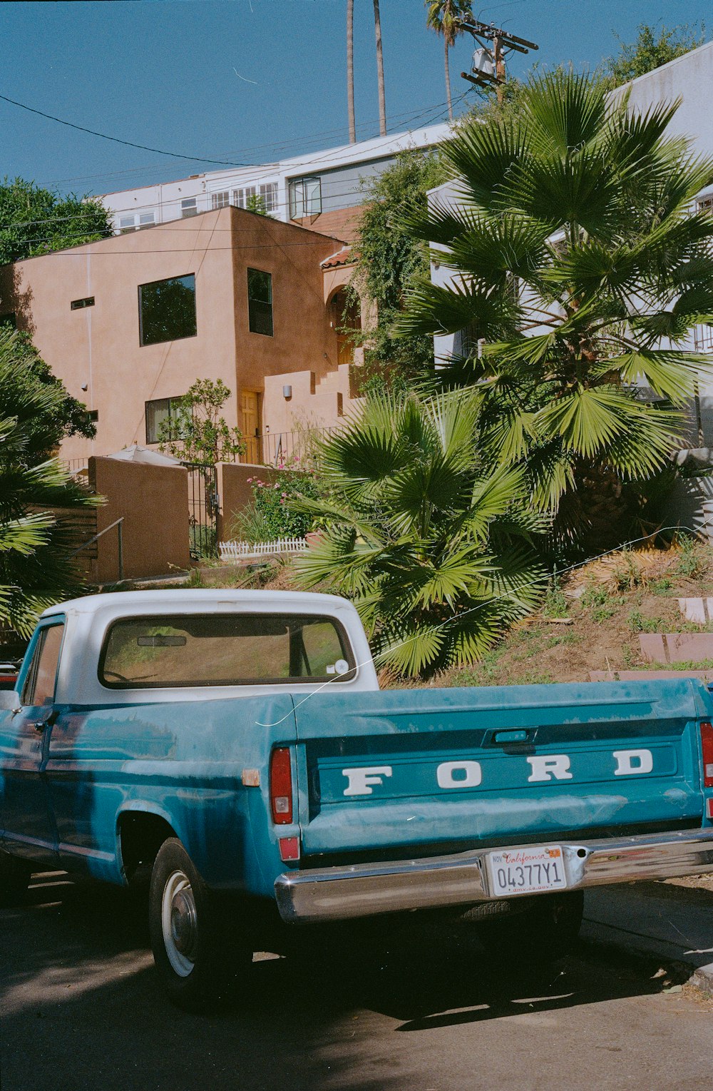 a blue ford pickup truck parked in front of a house