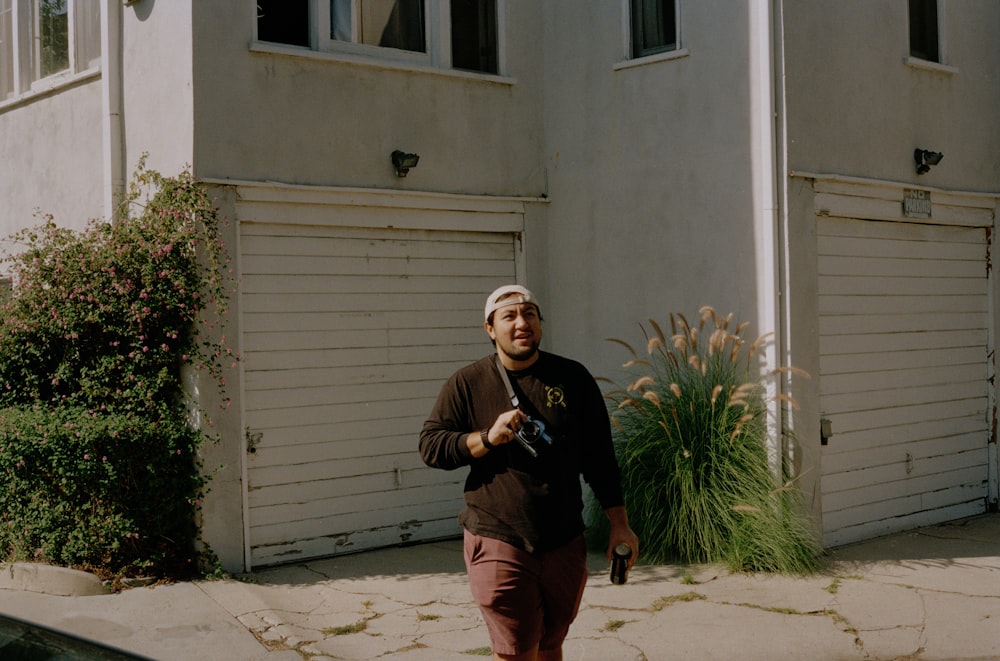 a man walking down a sidewalk with a cell phone in his hand