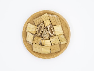 A wooden plate contains several pieces of cylindrical bamboo and two unique pieces with intricate inner patterns. The items are neatly arranged, showing varying shades of light brown and beige, and emphasizing natural textures.