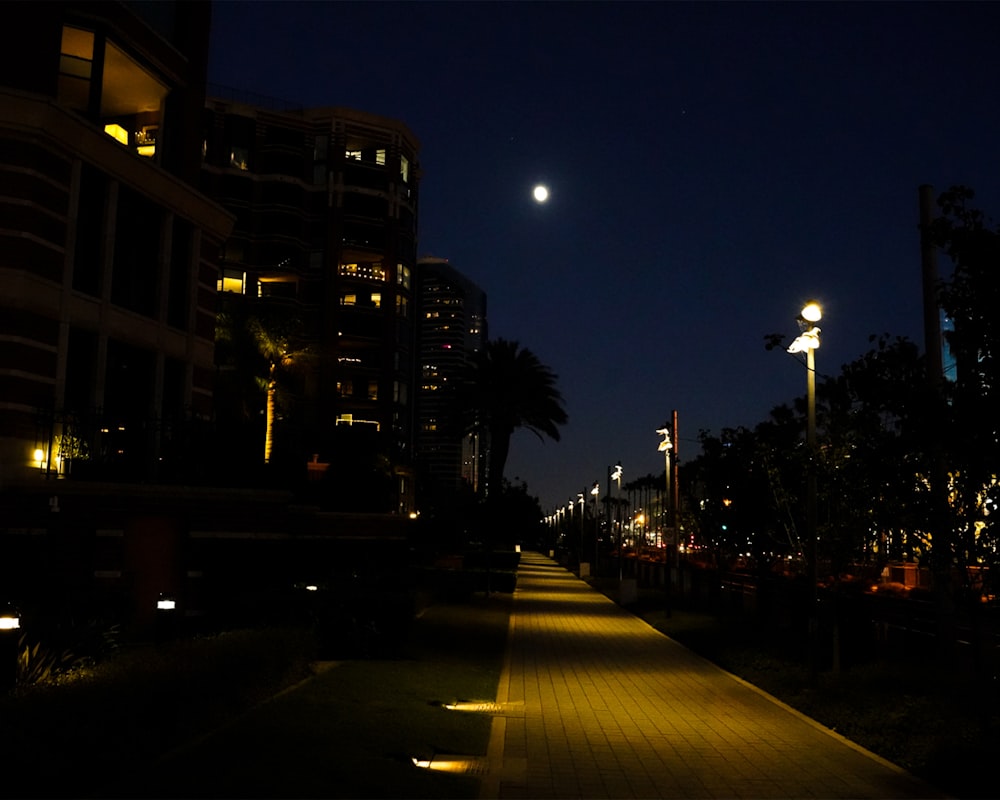 a city street at night with a full moon in the sky
