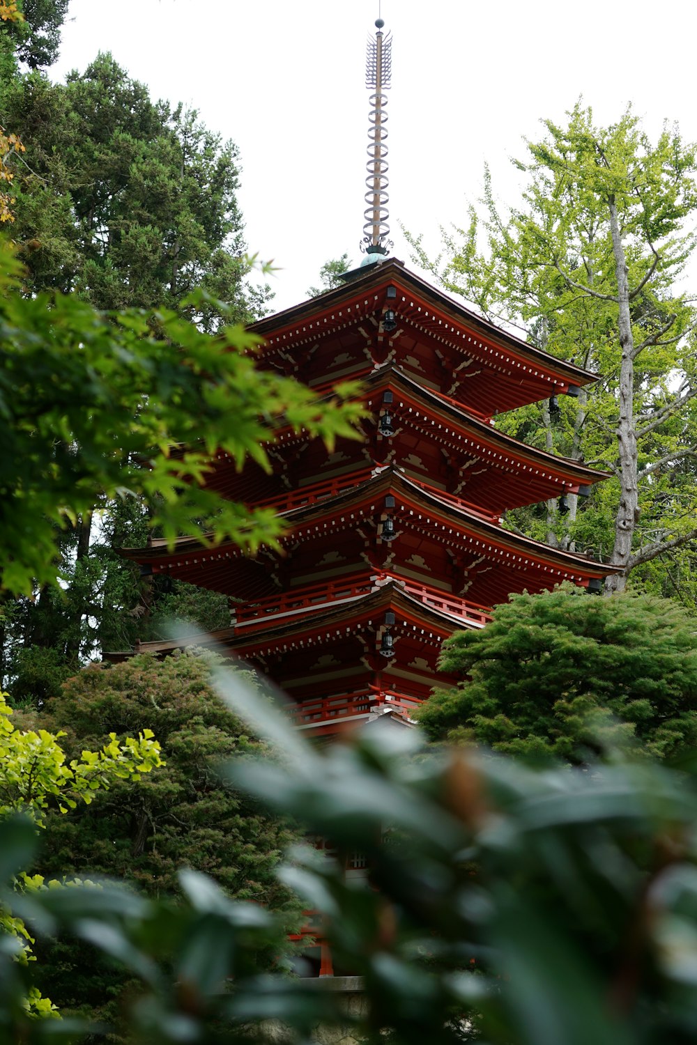 a tall red pagoda in the middle of a forest