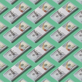 A pattern of stacks of one hundred dollar bills arranged neatly against a green background, creating a repetitive and organized visual.