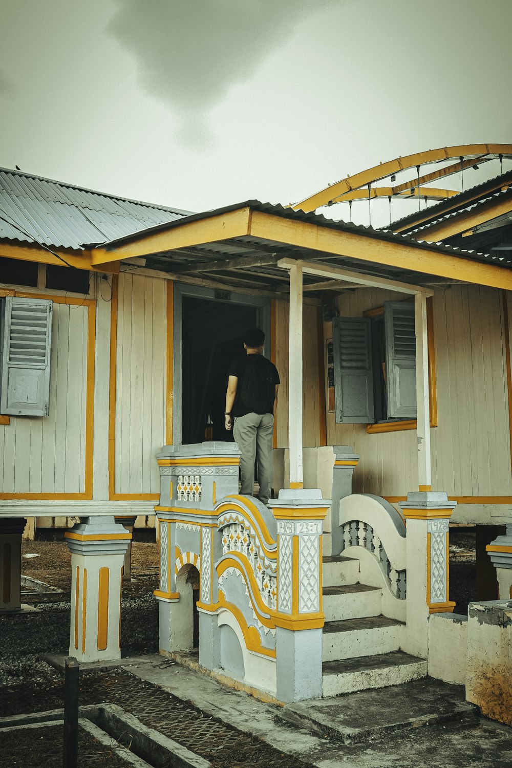 a man standing in the doorway of a yellow and white house