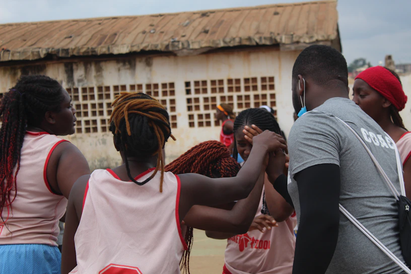 A close-knit group of young participants huddled together, hands stacked in a team cheer during an outdoor workshop.