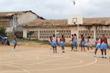 A group of girls in vibrant purple jerseys celebrating a basketball win on an outdoor court.
