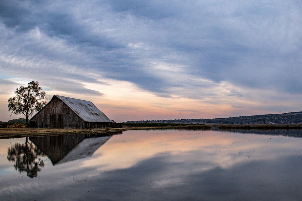 a barn sitting on top of a lake under a cloudy sky