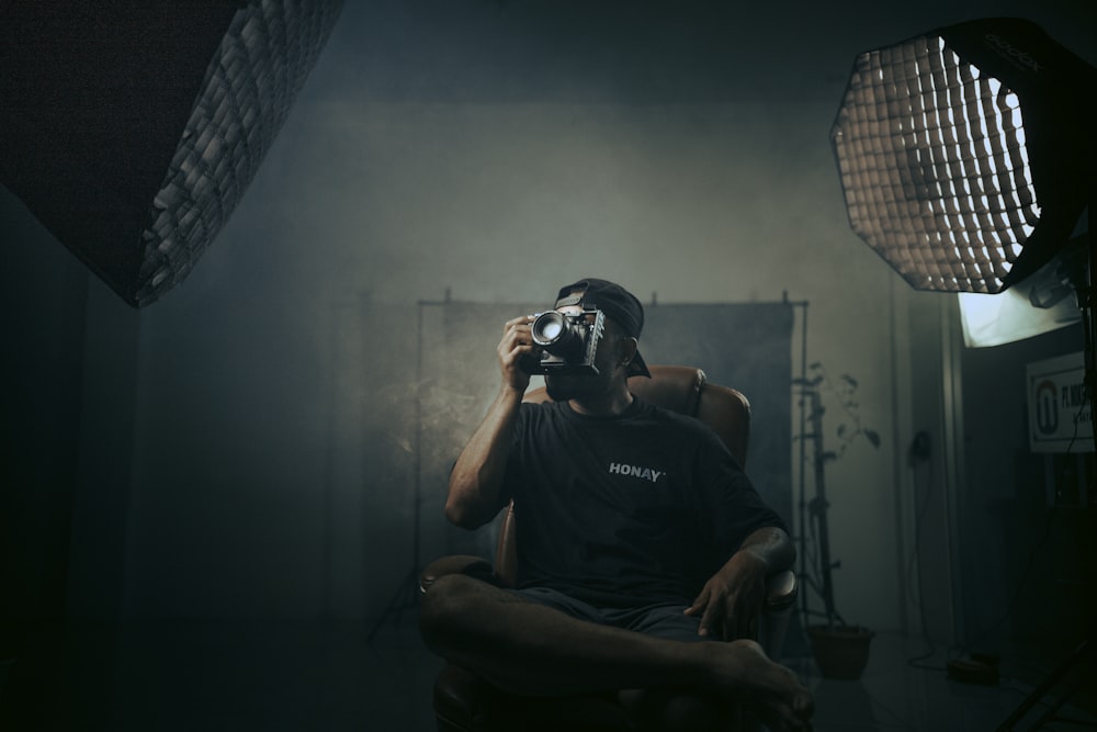 a man sitting in a chair holding a camera