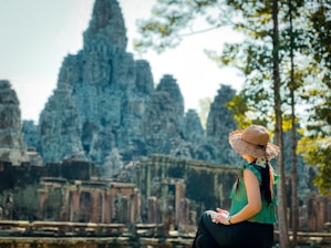a woman in a straw hat sitting on a rock